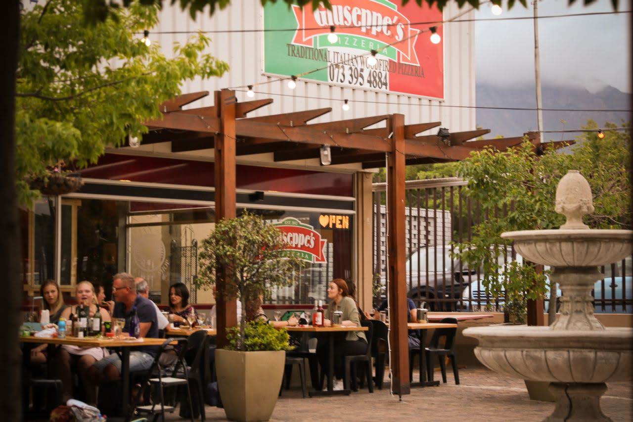 Giuseppe's Pizzeria outdoor eating area with people seated at tables.